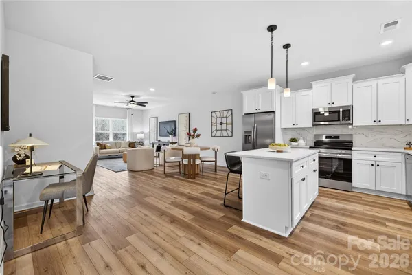 a kitchen with stainless steel appliances kitchen island granite countertop a stove a sink a dining table and chairs with wooden floor