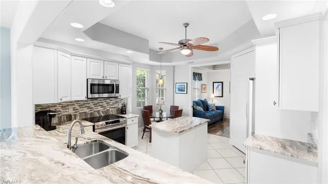a kitchen with stainless steel appliances kitchen island granite countertop a stove and a view of living room