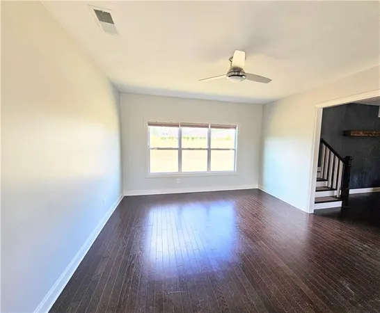 an empty room with wooden floor chandelier and windows