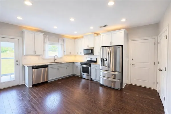 a large kitchen with stainless steel appliances wooden floors and white cabinets