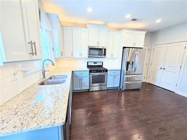 a kitchen with granite countertop a refrigerator and a sink
