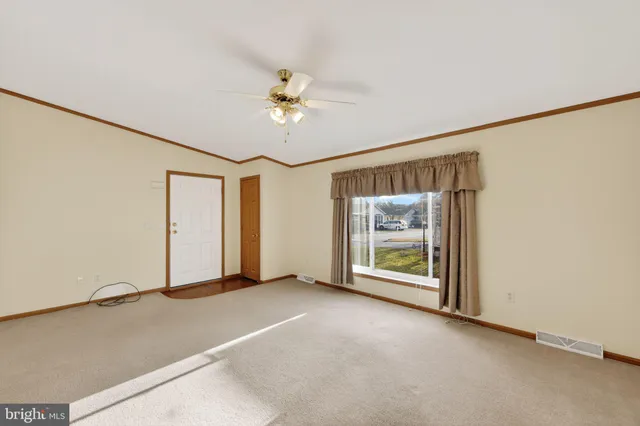 an empty room with chandelier fan and windows