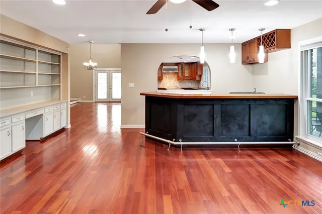 an empty room with wooden floor fireplace and windows