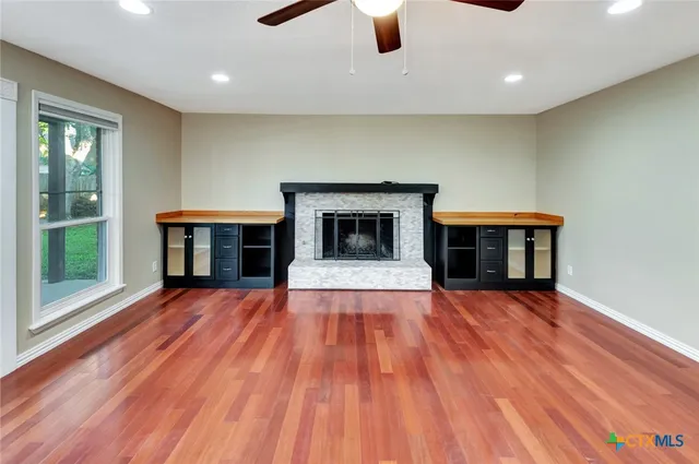 a view of an empty room with window and wooden floor