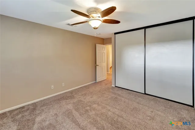 an empty room with a ceiling fan and a window