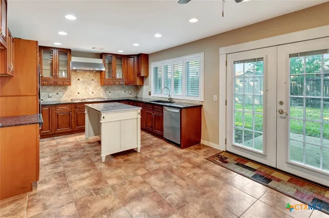 a kitchen with stainless steel appliances granite countertop a refrigerator and a stove top oven