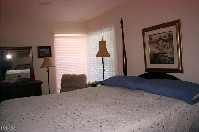a bedroom with a bed and a lamp on dresser