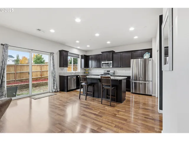 a kitchen with stainless steel appliances kitchen island granite countertop a refrigerator and a sink