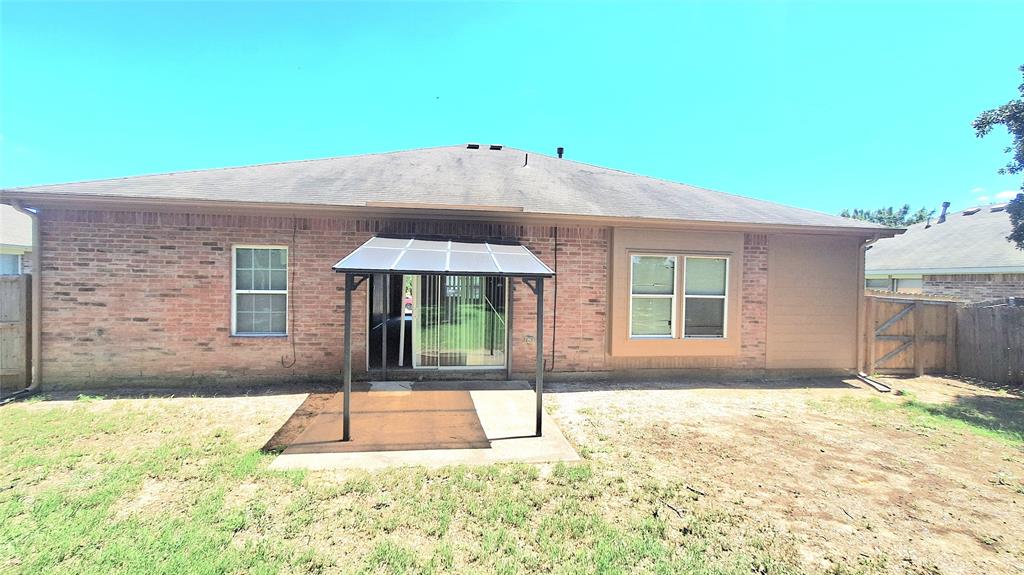 953 Hannah Way Dallas, TX 75253 - Photo 21 of 22 Rear exterior featuring brick and painted siding, a covered patio area, sliding glass door access, multiple windows, and a wood privacy fence