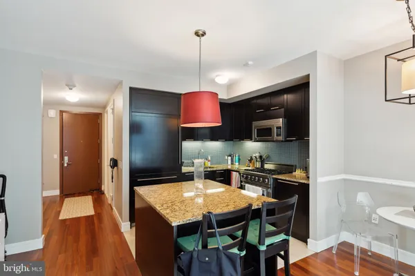 a kitchen with stainless steel appliances granite countertop a stove top oven a sink a dining table and chairs with wooden floor