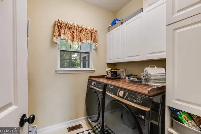 a utility room with stainless steel appliances wooden floor and a window