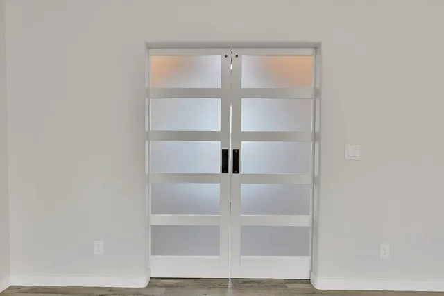 an empty room with wooden floor and windows