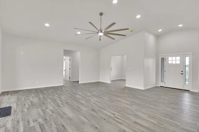 a view of an empty room with window and wooden floor