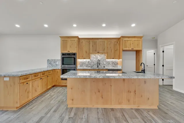 a large kitchen with stainless steel appliances granite countertop a stove a sink and a refrigerator