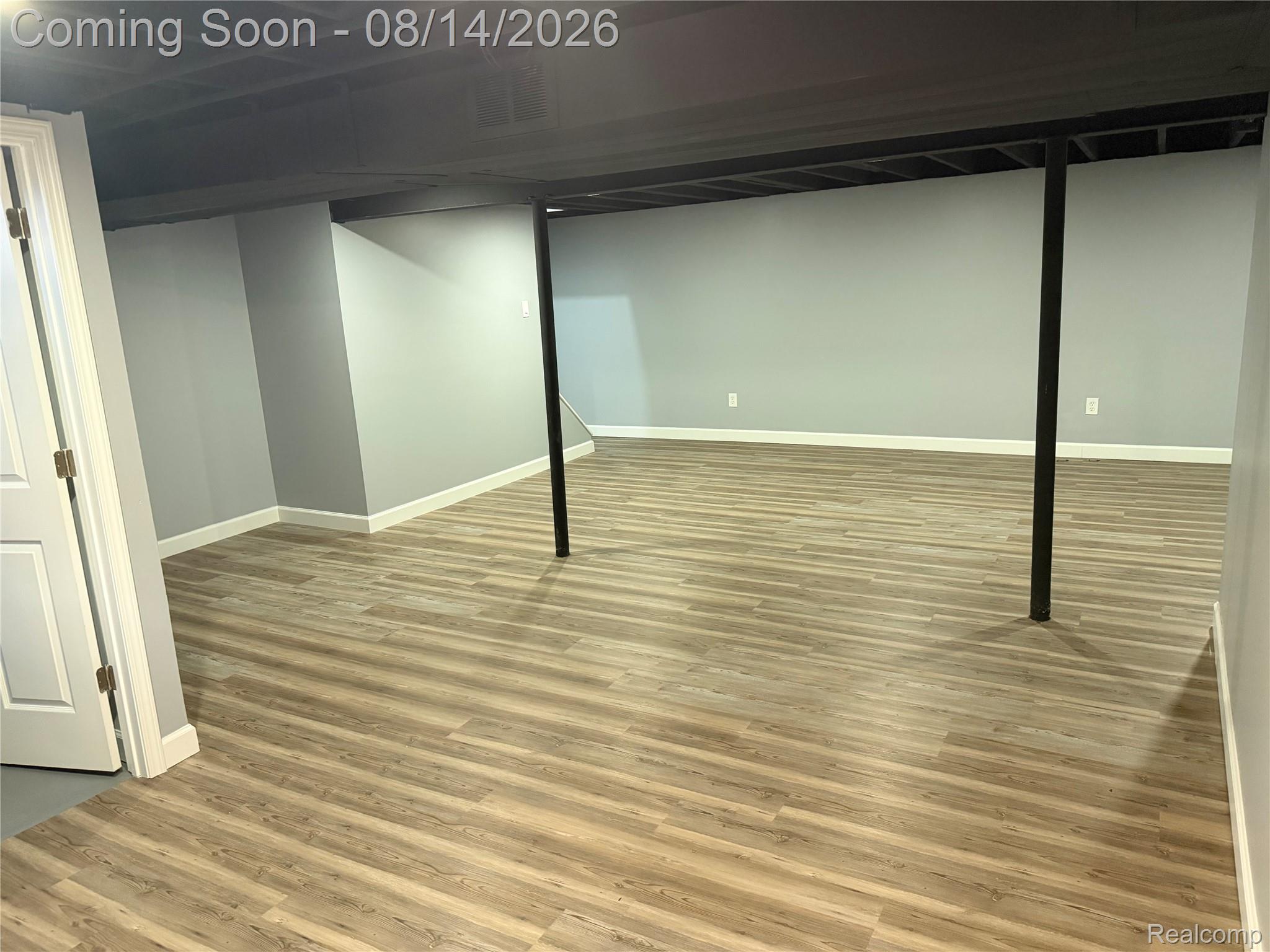 20698 Coachwood Road Riverview, MI 48193 - Photo 20 of 37 Spacious lower level featuring wood-finish flooring, light gray walls, white baseboards, and a painted exposed ceiling with structural columns