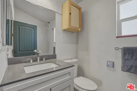 a bathroom with a granite countertop toilet sink and mirror