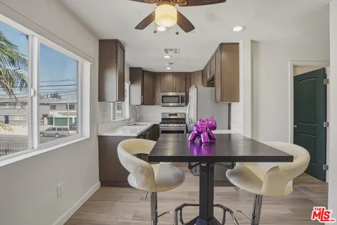 a kitchen with granite countertop a dining table chairs stainless steel appliances and cabinets