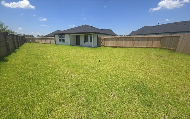 a view of a house with a yard and a large tree