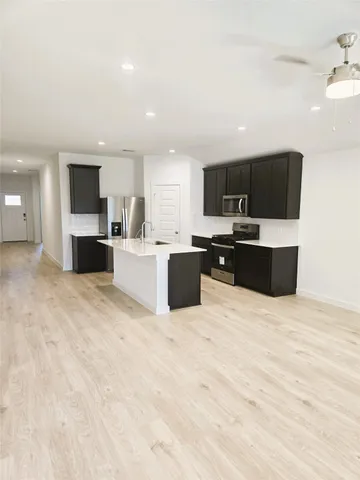 a large white kitchen with kitchen island granite countertop a stove a sink a microwave and a refrigerator