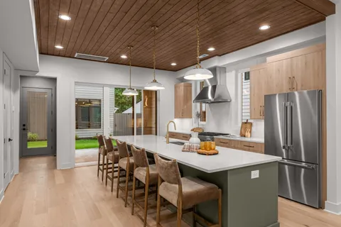 a kitchen with stainless steel appliances granite countertop a refrigerator a sink dishwasher a dining table and chairs with wooden floor