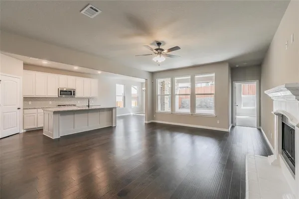 a view of an empty room with window and wooden floor