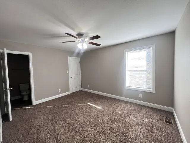 an empty room with windows and fan
