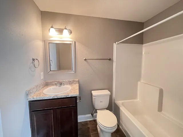 a bathroom with a sink vanity granite toilet and a mirror