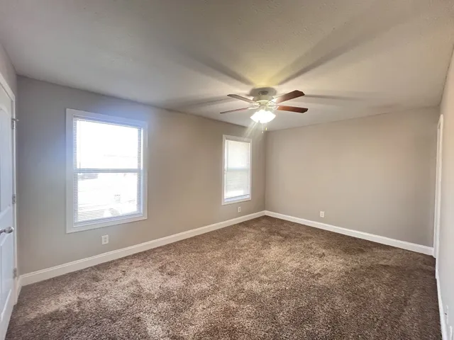 an empty room with windows and fan