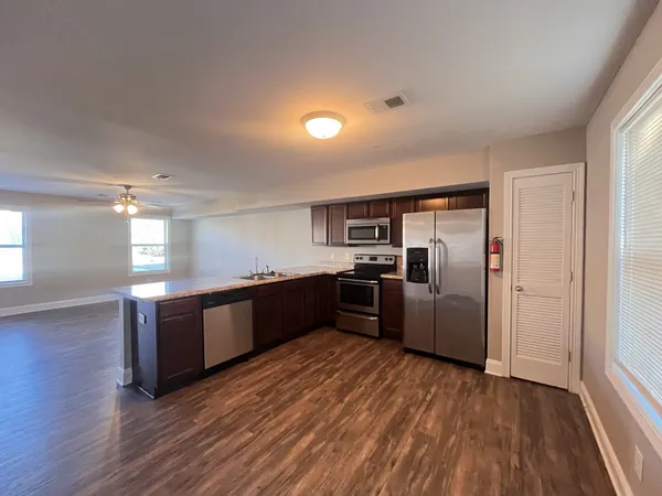 a kitchen with granite countertop a refrigerator and wooden floors