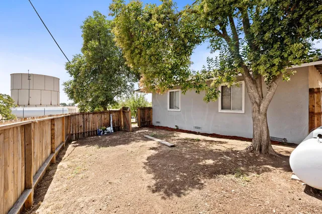 a view of a backyard with wooden fence and a large tree