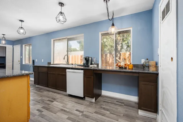 a kitchen with granite countertop a sink cabinets and wooden floor