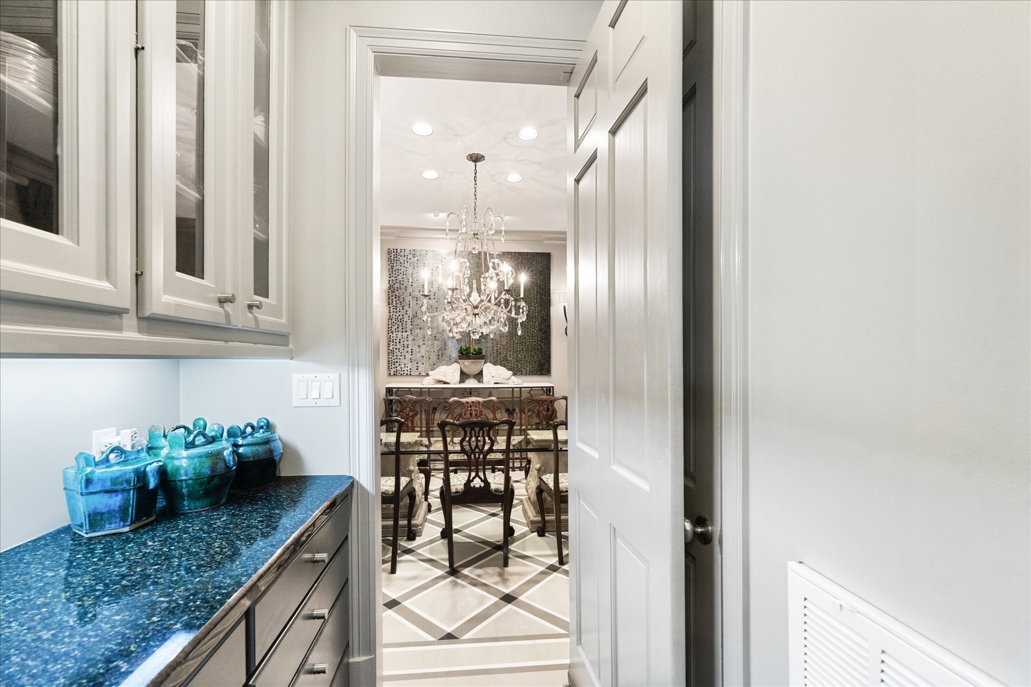2627 Sutton Court Houston, TX 77027 - Photo 15 of 34 The butler’s pantry offers additional storage and prep space, featuring glass-front cabinetry to showcase your favorite items and a seamless connection between the kitchen and dining room—perfect for both entertaining and everyday convenience. Behind the open door is the walk-in pantry, where your organizational dreams come true.