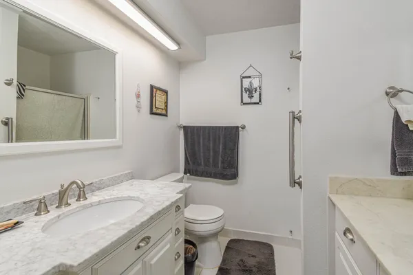 a bathroom with a granite countertop toilet sink and mirror