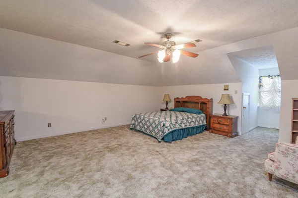a spacious bedroom with a bed and ceiling fan