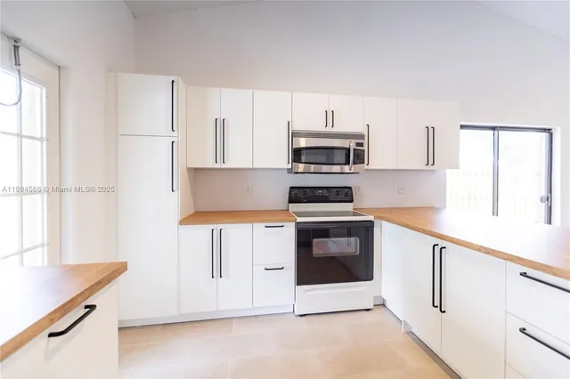 a kitchen with stainless steel appliances a stove a microwave a sink and white cabinets