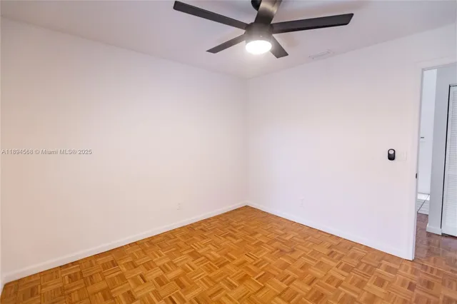 an empty room with a fan & a ceiling fan