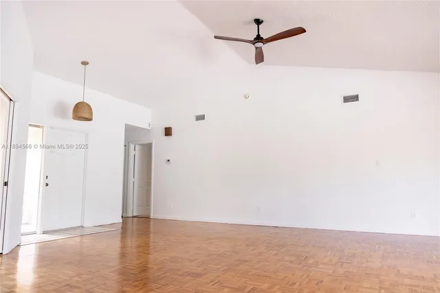a view of an empty room with wooden floor and windows