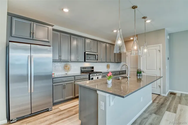 a kitchen with a sink a center island cabinets and stainless steel appliances