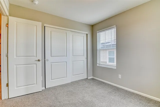 a view of an empty room with closet and a window