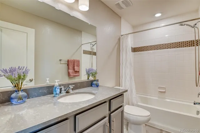a bathroom with a granite countertop sink a toilet and shower