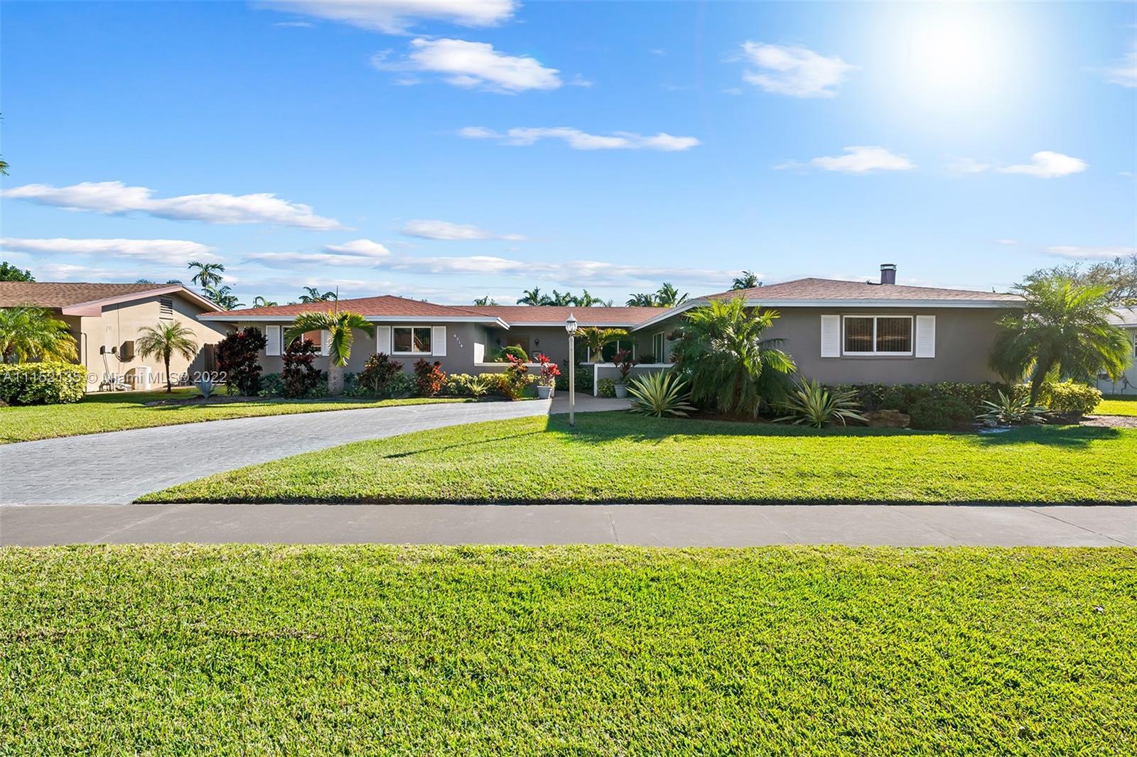 a view of an house with a big yard and palm trees