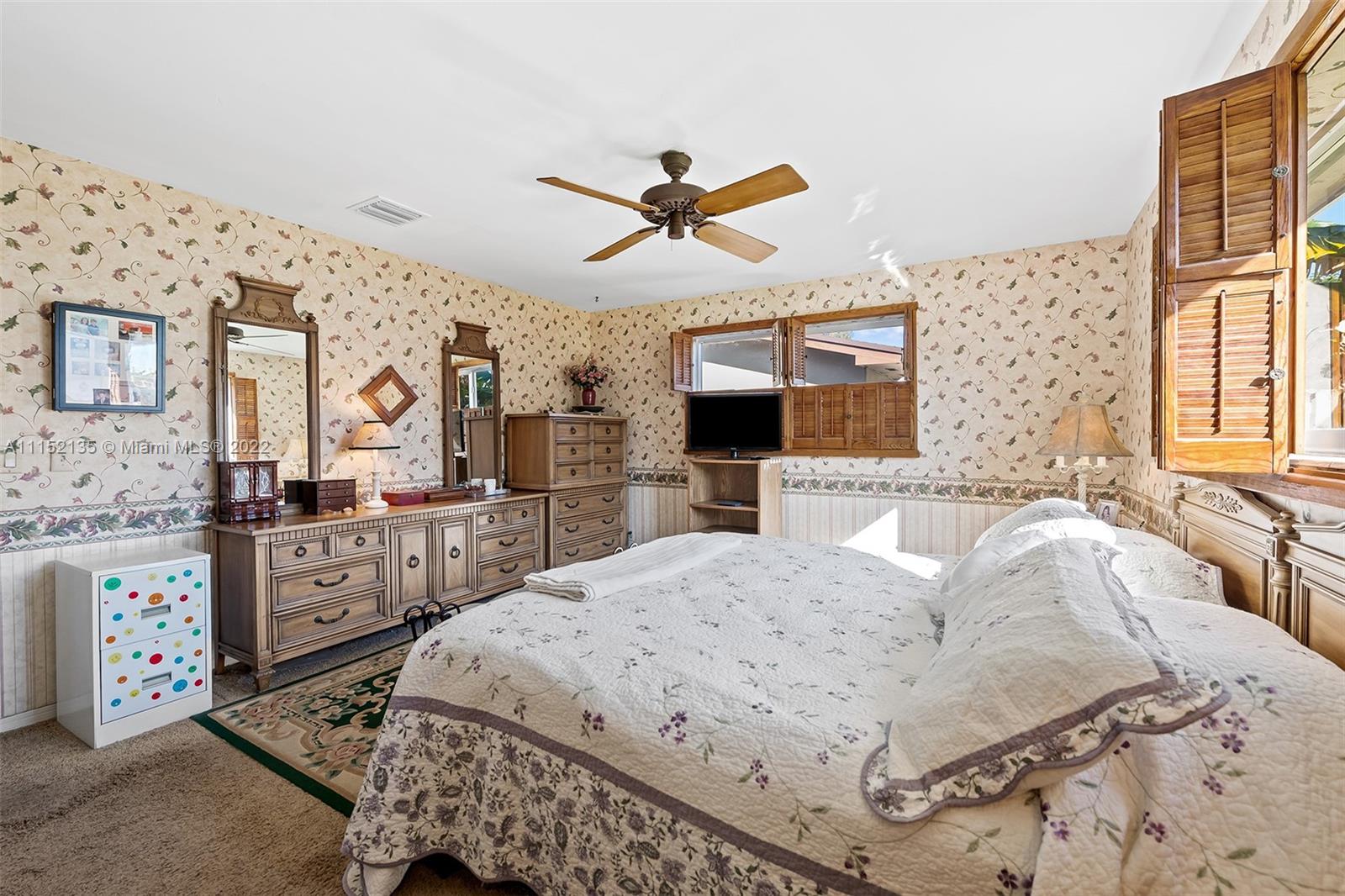 4314 Fillmore Street Hollywood, FL 33021 - Photo 17 of 27 a spacious bedroom with a bed a dresser and a chandelier