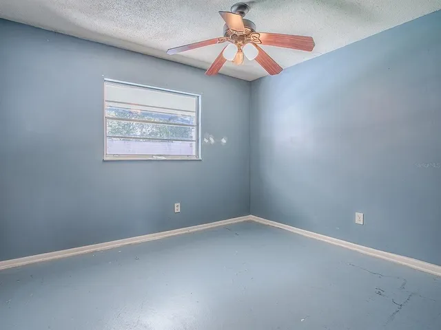 an empty room with a window and a fan