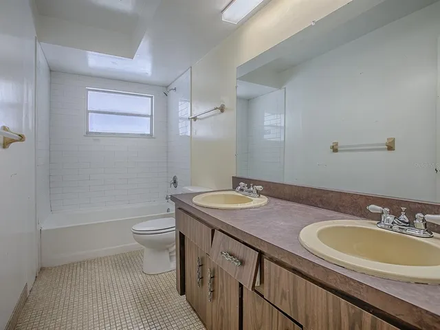 a bathroom with a granite countertop sink a toilet a mirror and bathtub