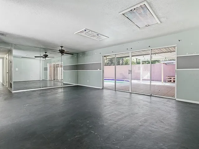 an empty room with wooden floor and windows with curtains