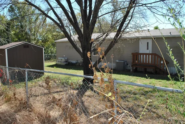 a view of backyard with wooden fence and a large tree