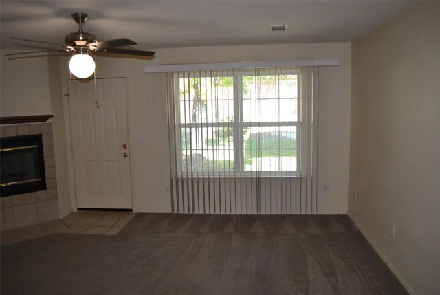 an empty room with wooden floor fan and windows
