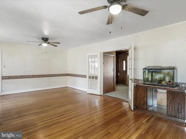 a view of a kitchen with wooden floor a sink a ceiling fan and a rug