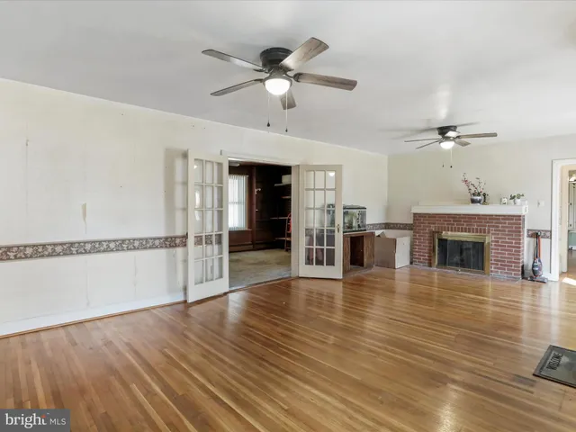 a view of an empty room with wooden floor and a fireplace