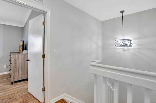a view of a hallway with wooden floor and chandelier